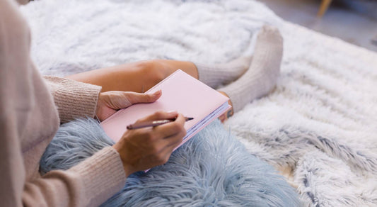Woman writing reflections in a notebook before bedtime